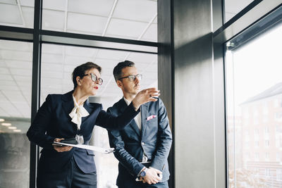 Senior businesswoman looking away while discussing with colleague in office