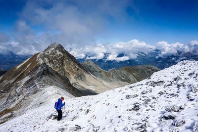 Hiker on snowcapped mountain against sky