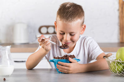 Smiling boy eating breakfast at home