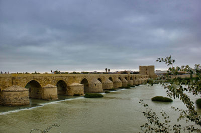 Arch bridge over river against sky