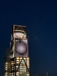 Low angle view of skyscraper against clear sky at night