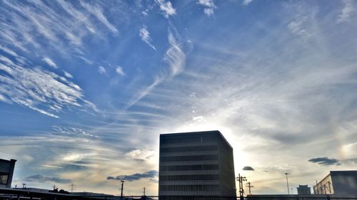 Low angle view of office building against cloudy sky