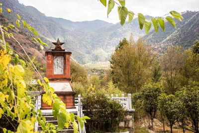 Built structure by trees and plants against sky