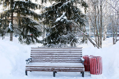 Empty bench on snow covered field during winter