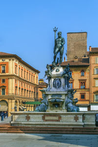 Statue against historic building in city against clear sky