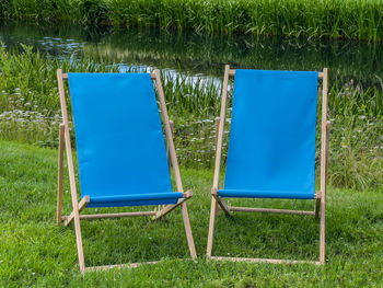 Empty chair on field by lake