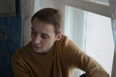 Side view of boy looking through window