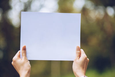 Close-up of hand holding paper against blurred background