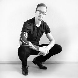 Portrait of young man sitting against wall