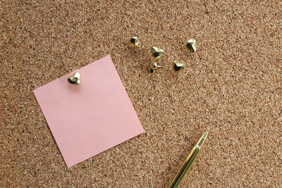 Close-up of adhesive note with pen on bulletin board