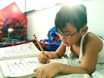 Boy studying while lying on bed at home