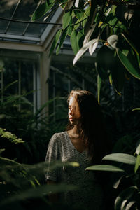 Portrait of a young woman amidst plants during sunset