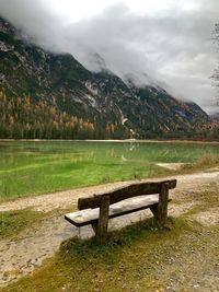Bench by lake against mountains