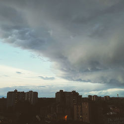 Buildings in city against storm clouds