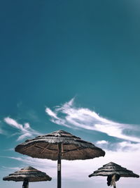 Traditional windmill on beach against blue sky