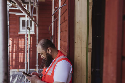 Bearded male construction worker using smart phone at site