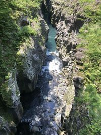 High angle view of river flowing amidst rocks in forest