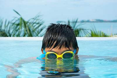 Portrait of boy swimming in pool against sky