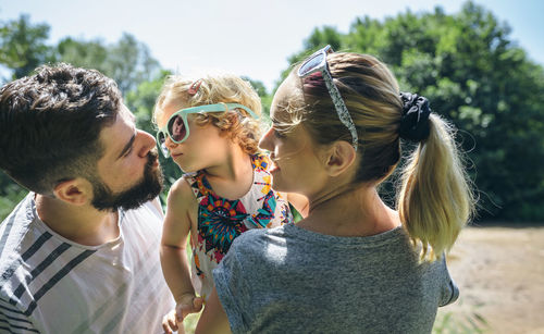 Little girl with sunglasses giving kisses to her parents