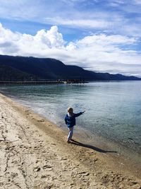 Boy playing by lake tahoe against cloudy sky