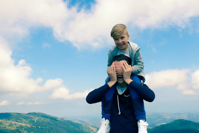 Happy boy standing against sky