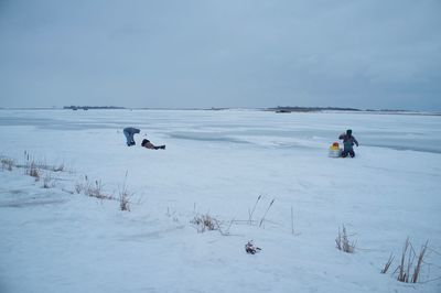 People on snowcapped field against sky