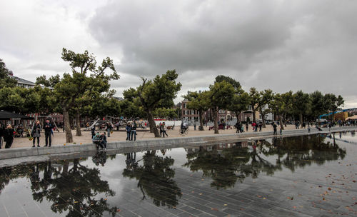 People on riverbank against sky