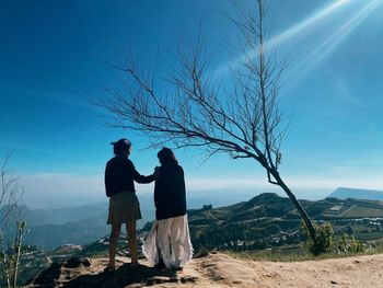 Rear view of girls standing on mountain against sky