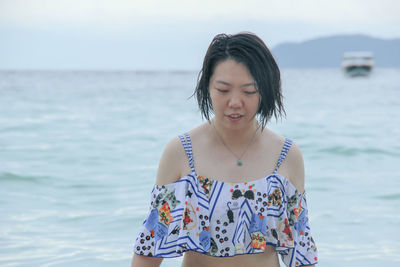 Close-up of young woman standing against sea