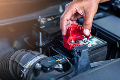 Cropped hands repairing car engine