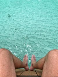 Low section of man sitting by swimming pool