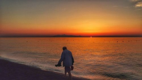 Man walking at beach during sunset