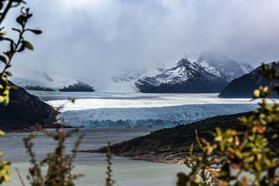 Scenic view of sea and snowcapped mountains against sky