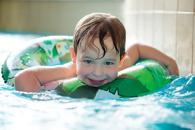 Portrait of happy boy swimming with inflatable ring in pool