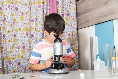 Young boy is working with the microscope and examines different things.