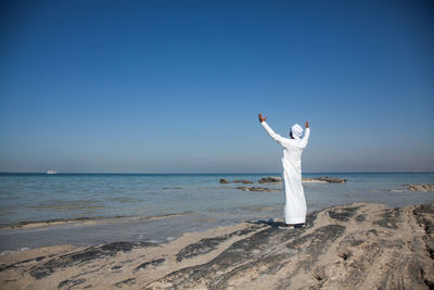 Woman standing on beach against clear sky