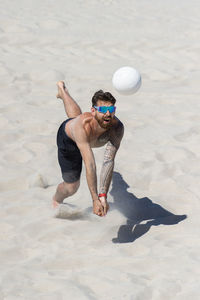 Full length of shirtless man with ball on beach
