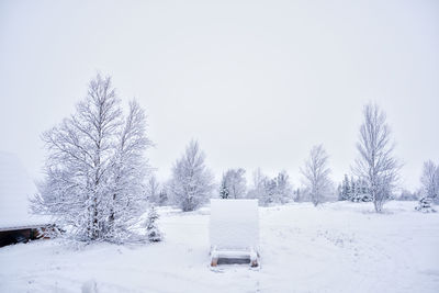 Snow covered trees on field against sky during winter