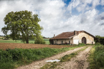 View of house in field against cloudy sky