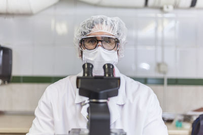 Close-up front view of man scientist looking through microscope at laboratory