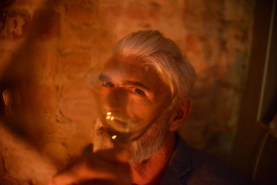 Portrait of a man holding wineglass in front of his face