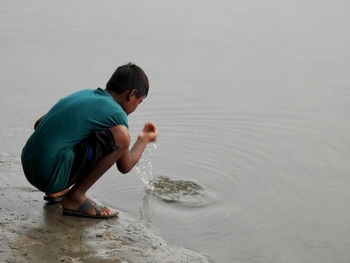 Side view of boy sitting in riverside 