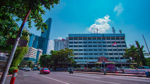 Road by buildings in city against sky