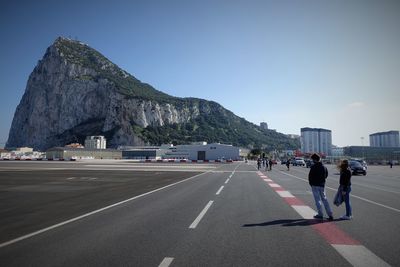 People standing on road against clear sky