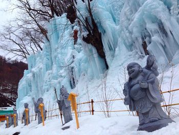 Laughing buddha and other religious statues in snow