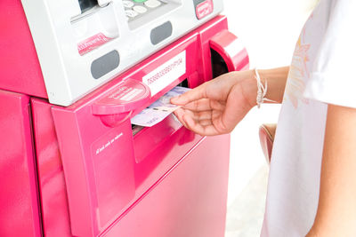 Midsection of woman removing paper currency from atm machinery