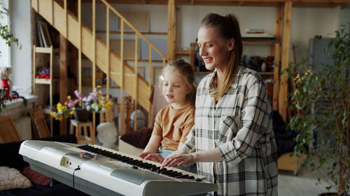 Mother and daughter playing piano at home