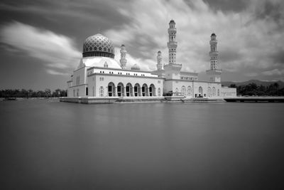 Kota kinabalu city mosque by lake against cloudy sky