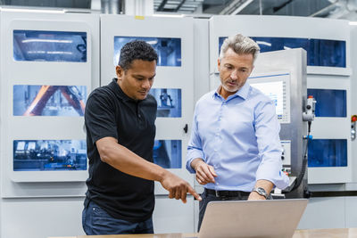 Businessman discussing over laptop with maintenance engineer in factory