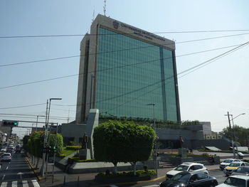 Cars on road by buildings against sky